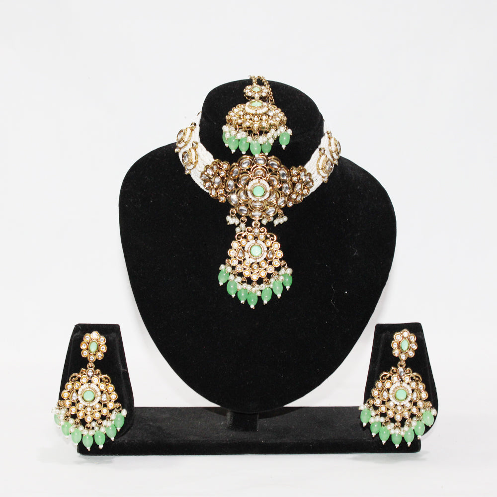 Jewelry set with necklace, earrings, and tikka on a black stand against a white background