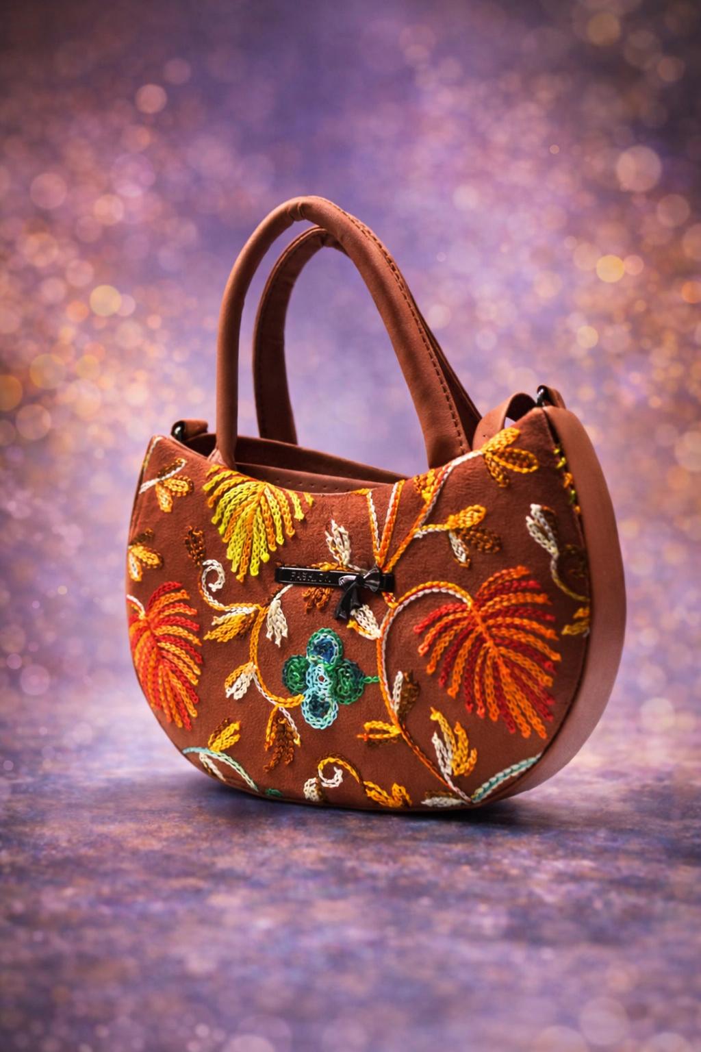 Brown handbag with floral embroidery on a textured purple background