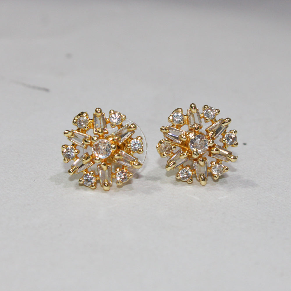 Gold earrings with clear gemstones on a light gray background