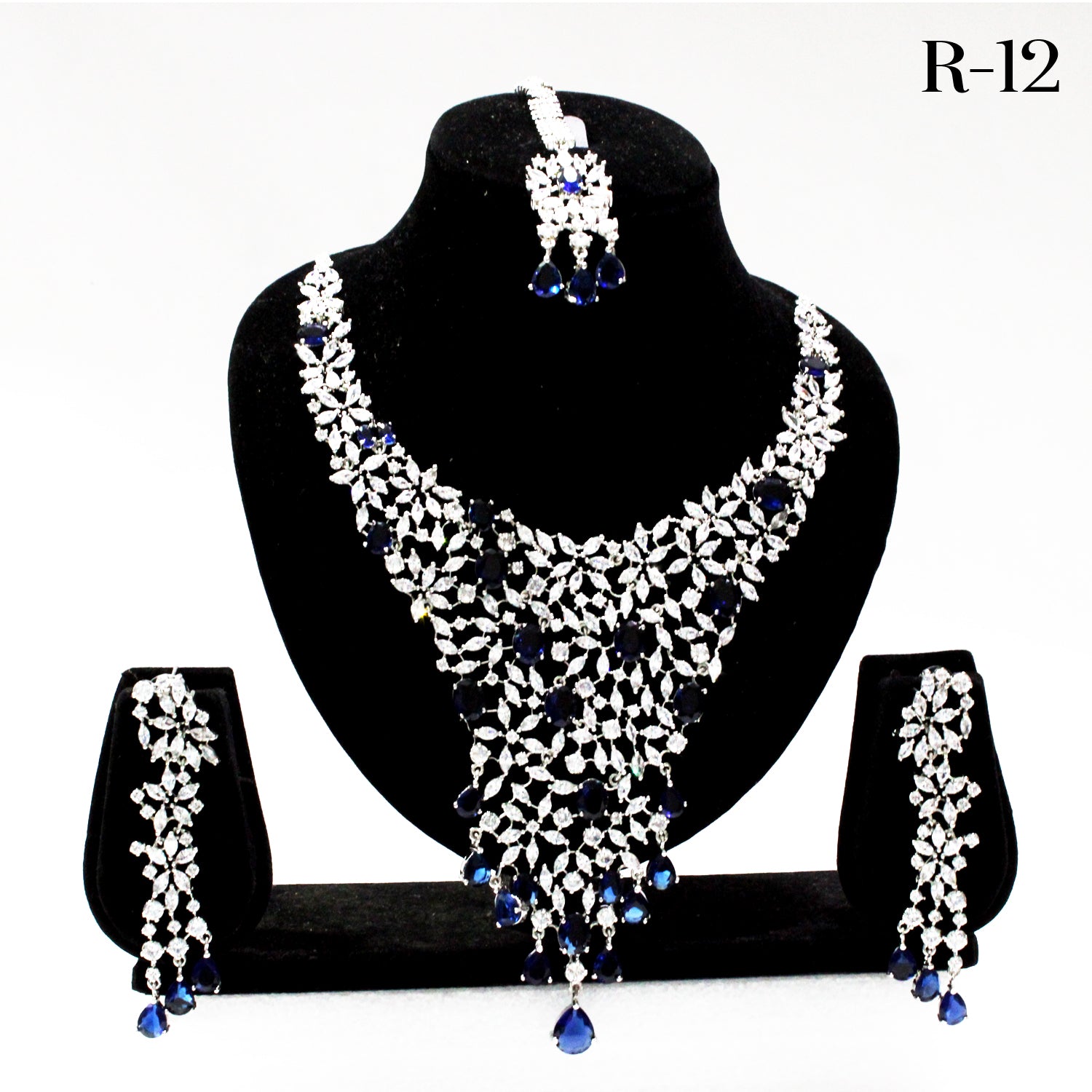 Jewelry set with necklace, earrings, and bangles on a black stand against a white background.