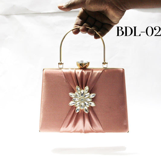 Pink clutch bag with a decorative flower on a white background, held by a hand.
