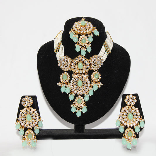 Jewelry set with necklace, earrings, and tikka on a black stand against a white background