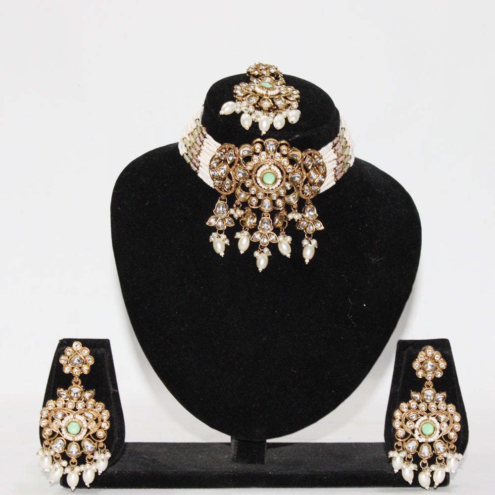 Jewelry set with necklace, earrings, and tikka on a black stand against a white background