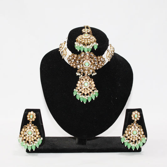 Jewelry set with necklace, earrings, and tikka on a black stand against a white background