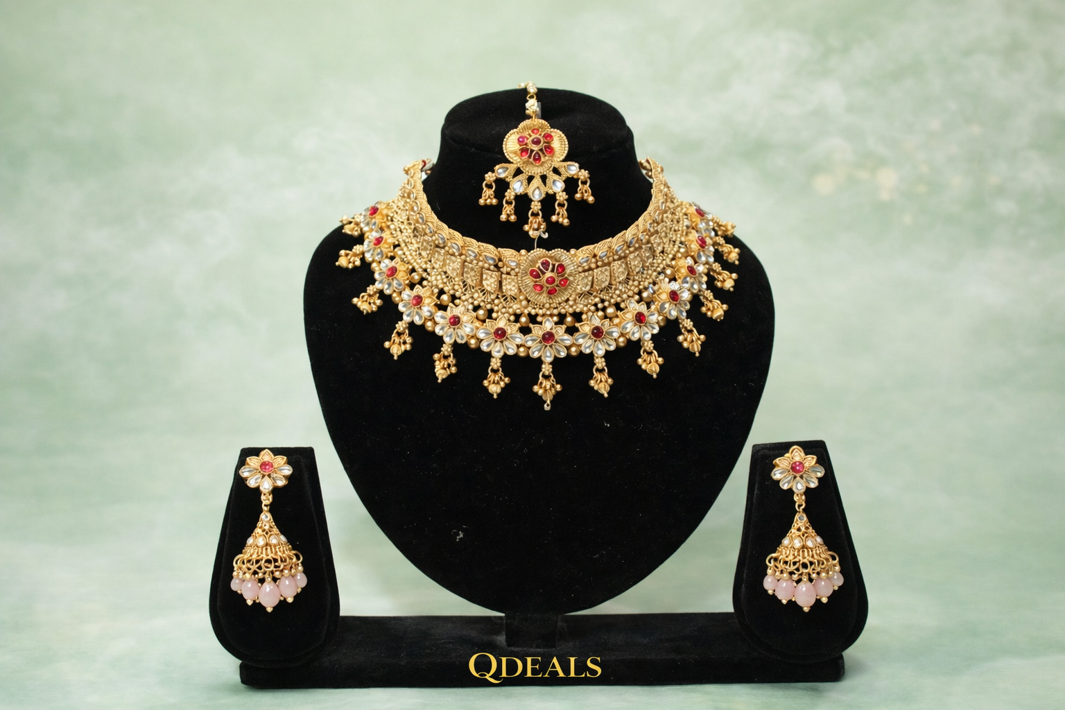 Gold necklace and earrings set on a black stand with 'QDeals' branding against a light green background.