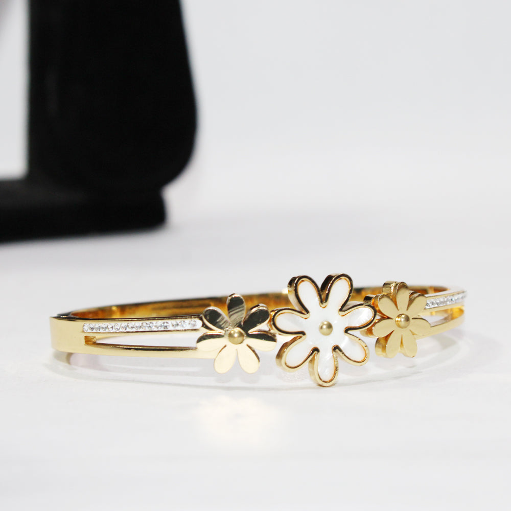 Gold bracelet with floral designs on a white surface