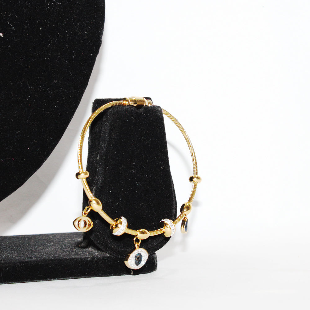 Gold bracelet with small circular charms on a black velvet stand against a white background