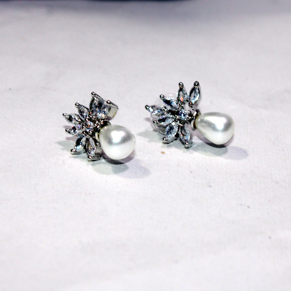 Pair of earrings with star-shaped top and pearl-like bottom on a light background