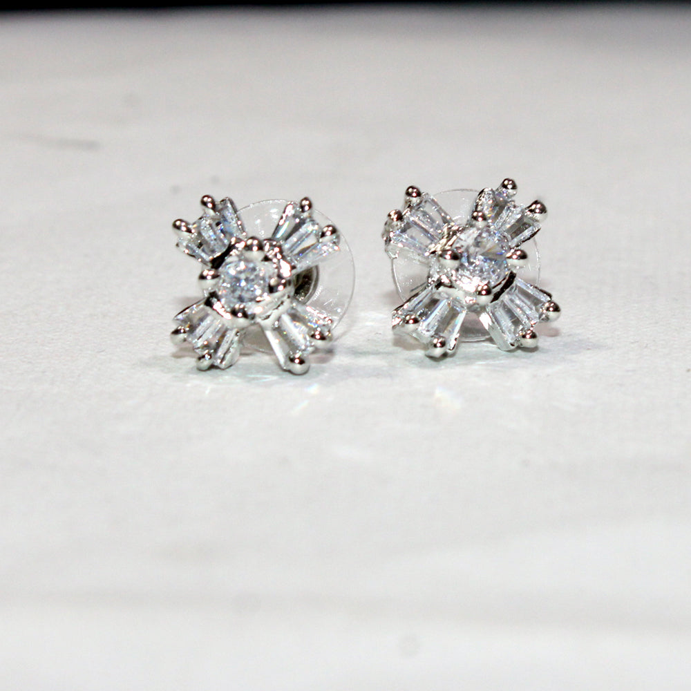 Pair of silver earrings with clear gemstones on a light gray background