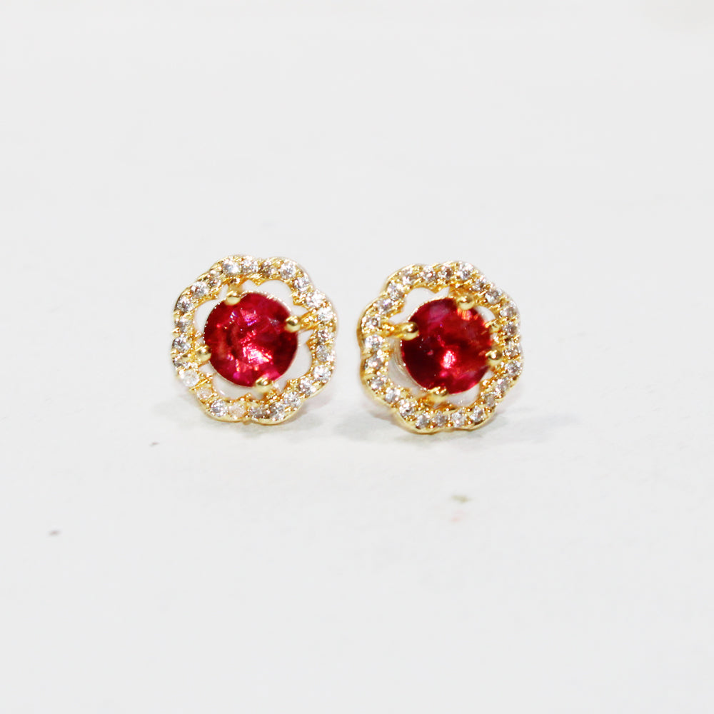 Gold earrings with red gemstones on a white background