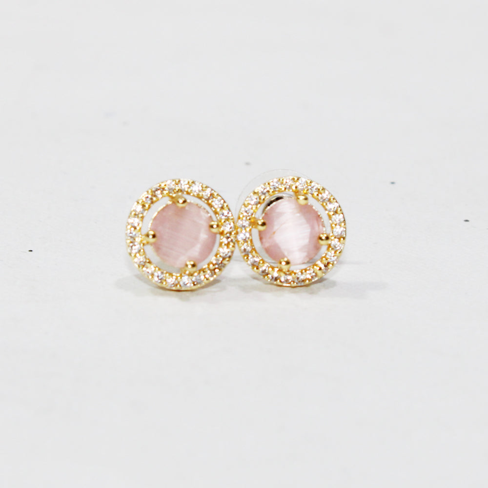 Pair of earrings with pink stones and gold accents on a light gray background