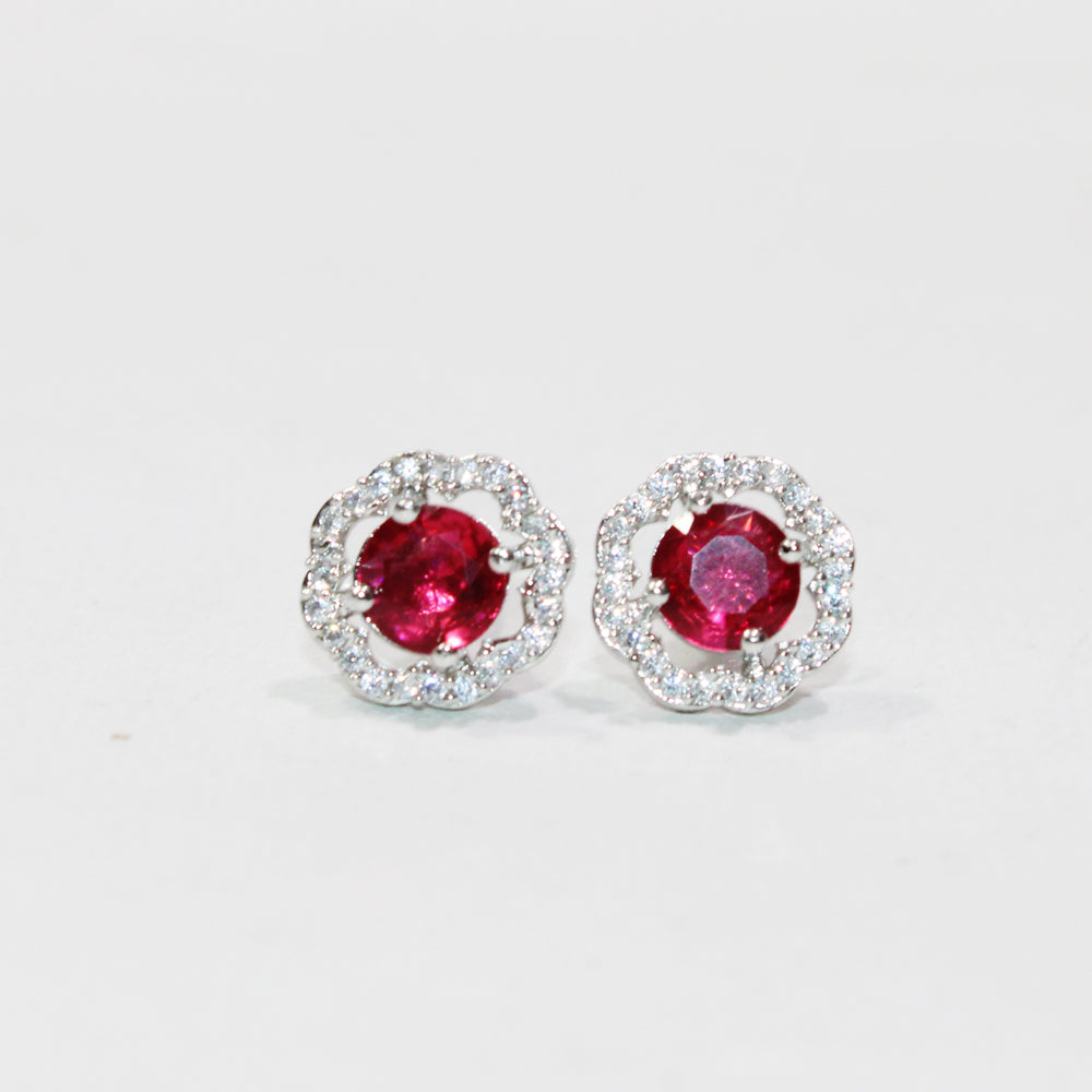 Pair of earrings with red gemstones and silver surrounds on a white background