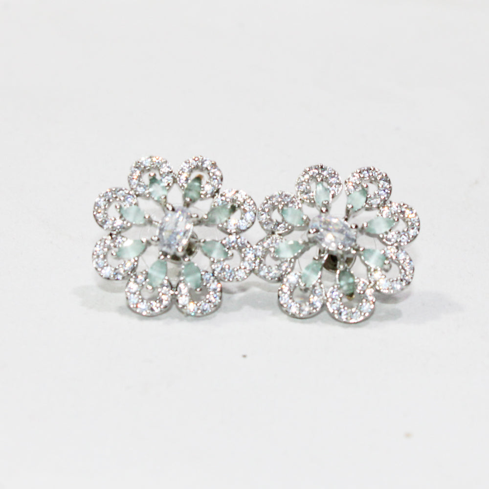 Pair of floral earrings with gemstones on a light gray background