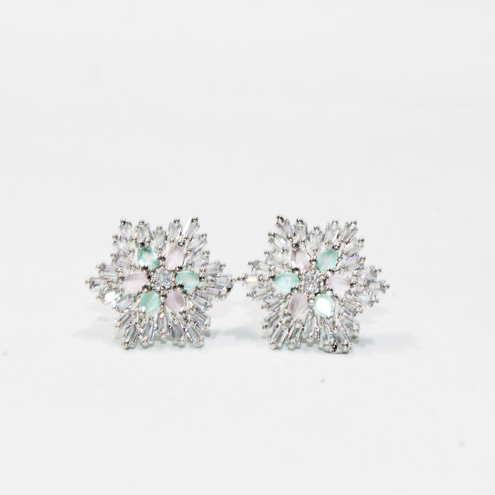 Pair of floral earrings with gemstones on a light gray background