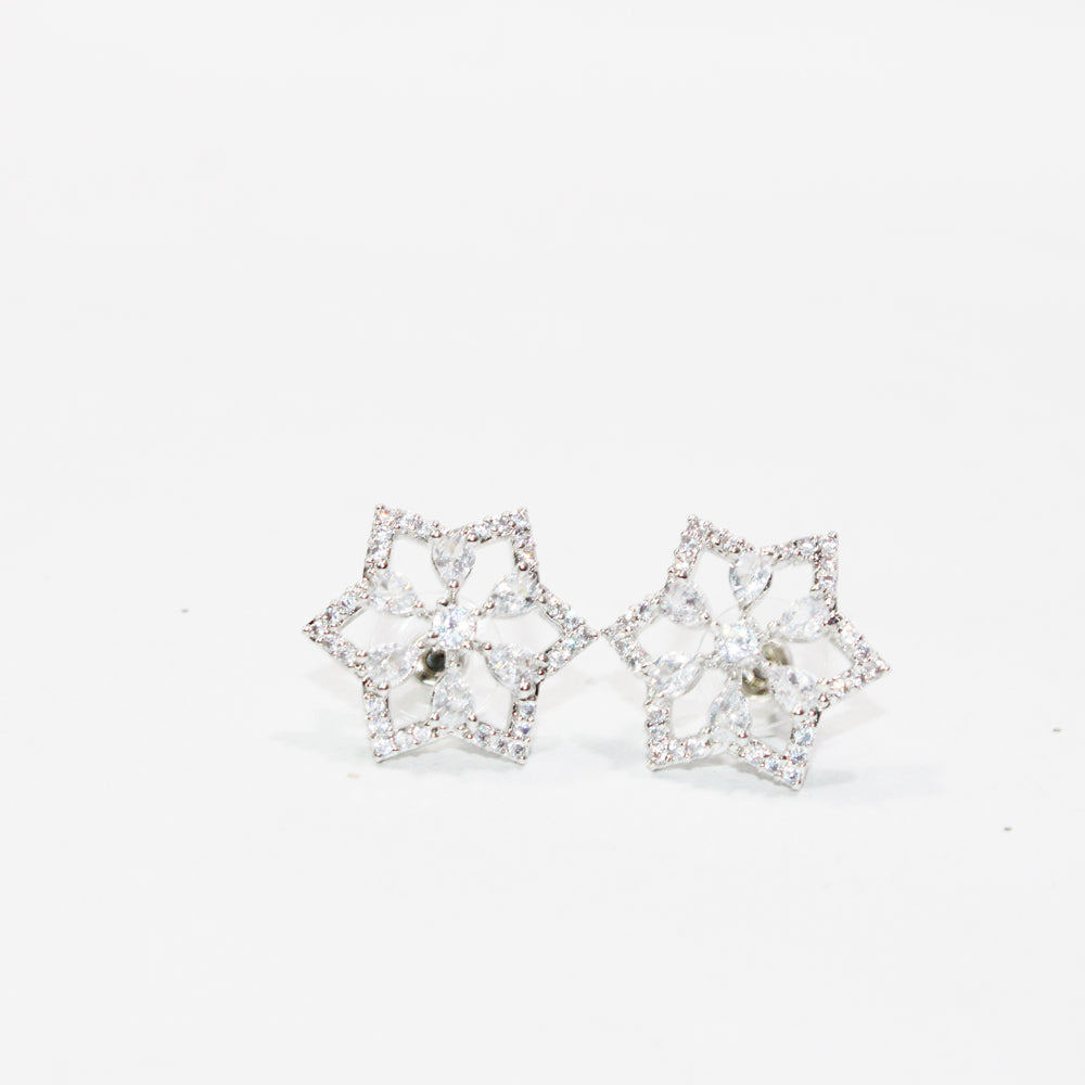 Pair of star-shaped earrings with clear stones on a white background