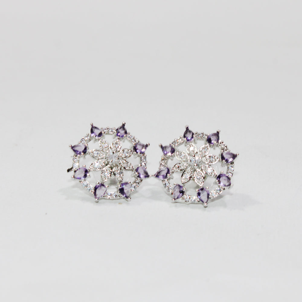Pair of silver earrings with purple gemstones on a light gray background