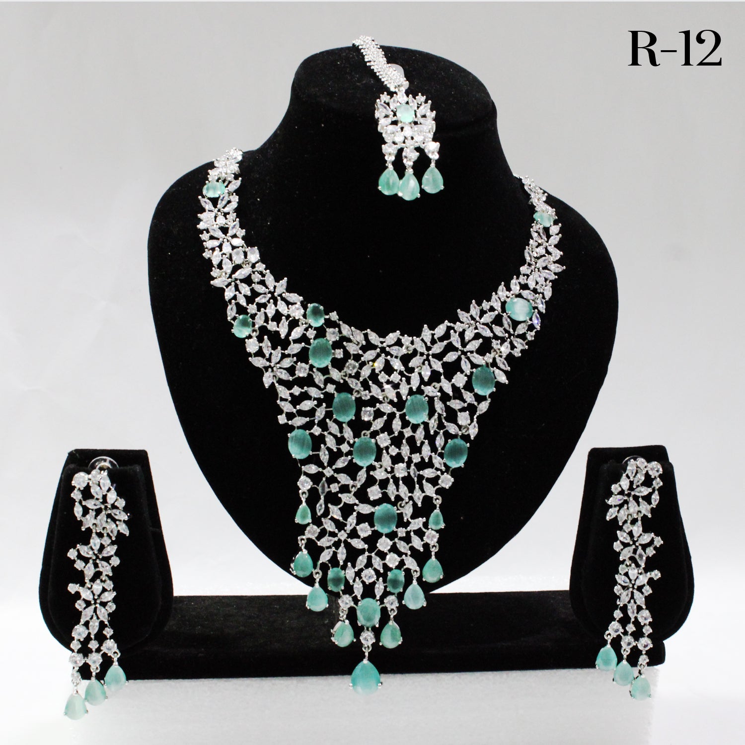 Jewelry set with necklace, earrings, and tikka on a black stand against a white background.