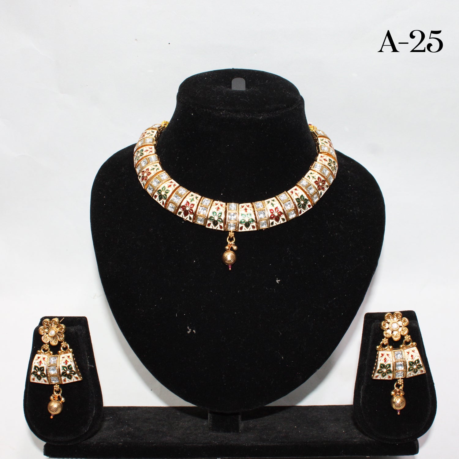 Jewelry set with necklace and earrings on a black stand against a white background